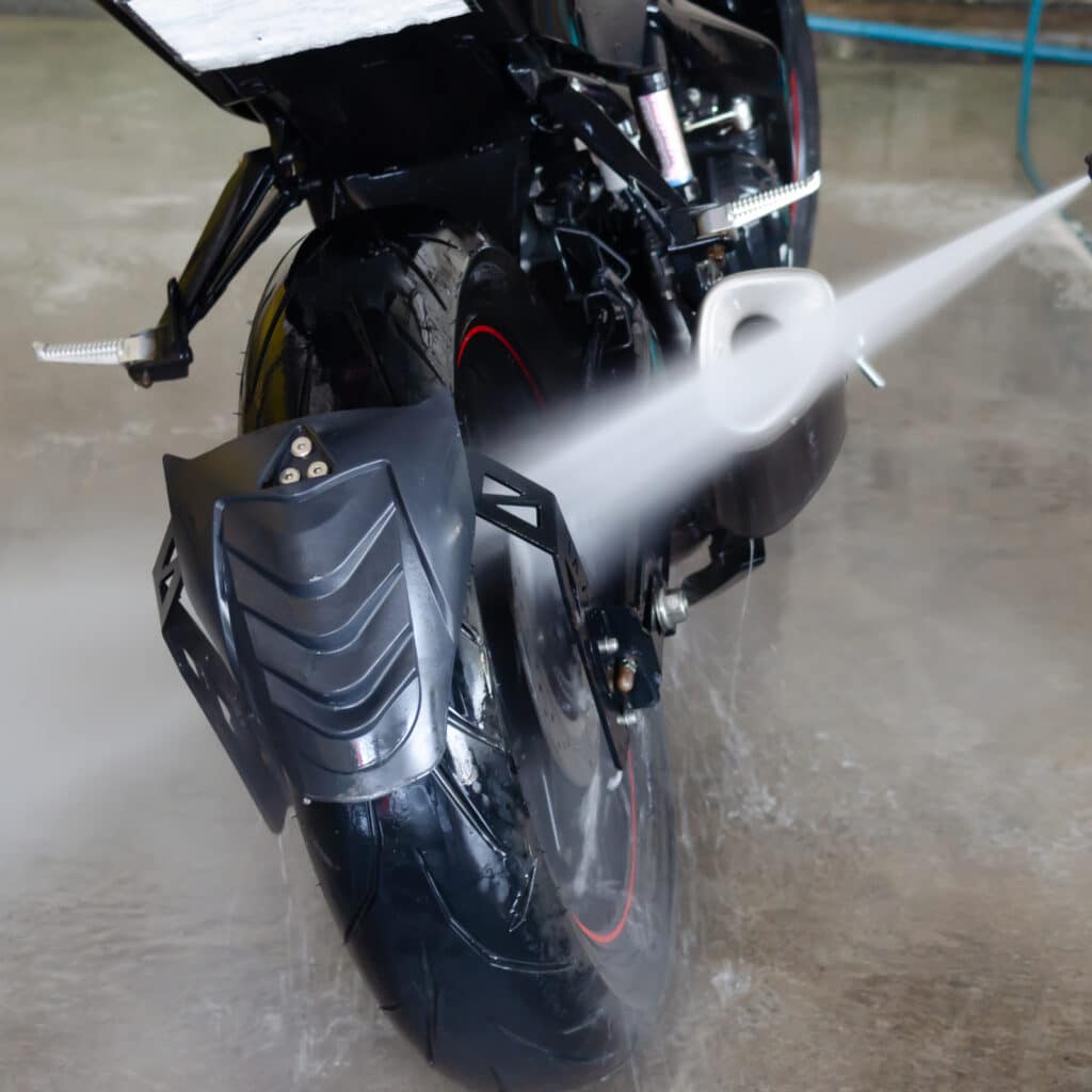 Nettoyage Haute Pression Moto Noire Roue Arrière Nettoyage d'une moto noire avec un nettoyeur haute pression ciblant la roue arrière et le garde-boue.
